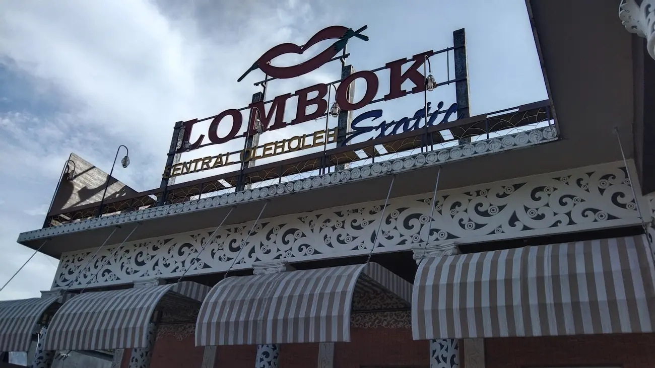 Papan nama Lombok Exotic di atas fasad berukir putih